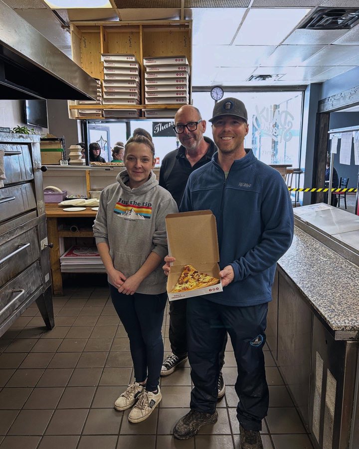 Brock with staff behind the counter at a local pizza shop