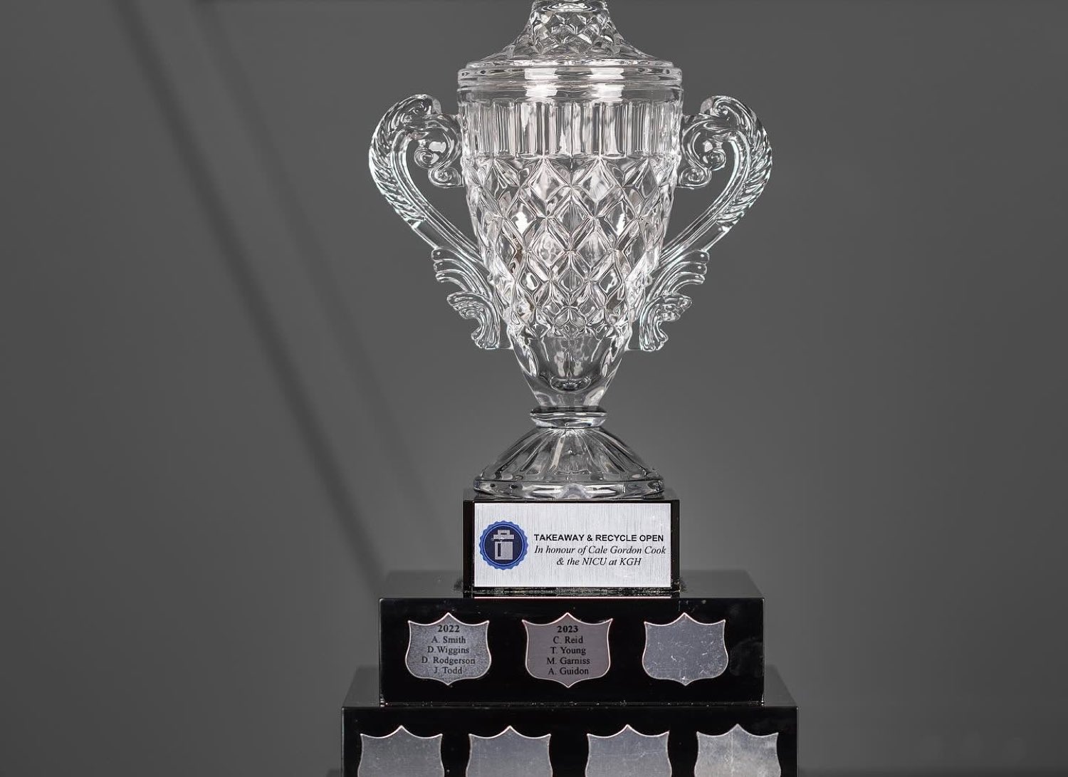 The TakeAway & Recycle Open crystal cup, engraved in honour of Cale Gordon Cook and the NICU at KGH, with winning teams from 2022 and 2023 on the base