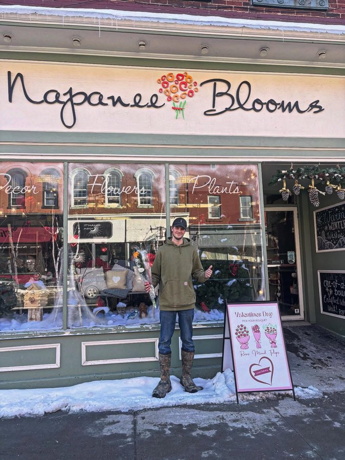 Brock holding a bouquet outside Napanee Blooms flower shop in winter