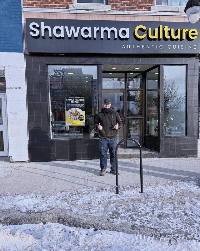 Brock outside Shawarma Culture, an authentic cuisine restaurant, on a snowy Kingston sidewalk