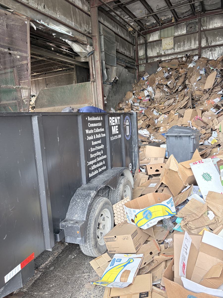 The trailer backed into a recycling facility beside a mountain of flattened cardboard and paper