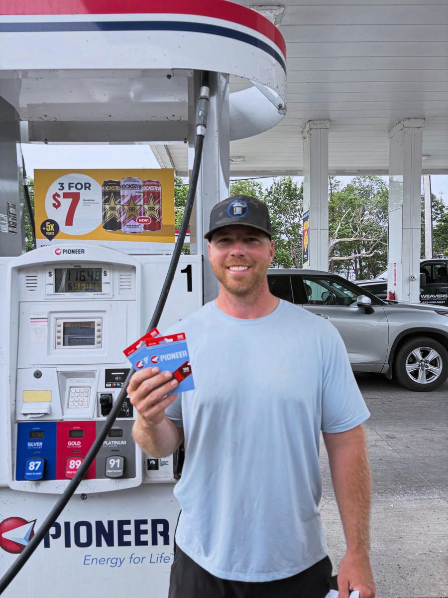 Brock Cook at a Pioneer gas station holding a handful of fuel gift cards