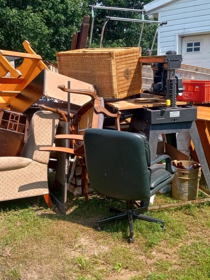 A yard full of old chairs, tables and a workbench staged for removal