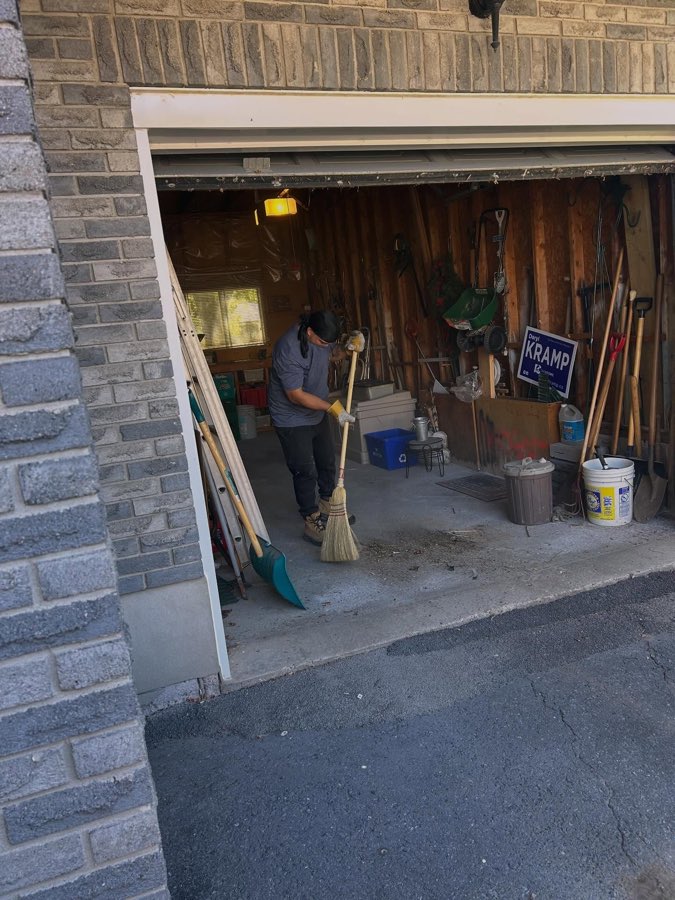 A crew member sweeping out a garage after the cleanout is finished