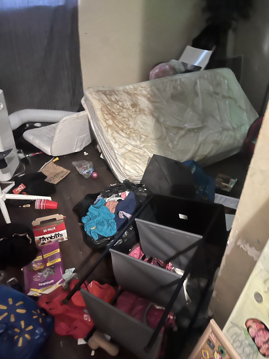 A bedroom left full of old mattresses, bins and clothing after a tenant moved out