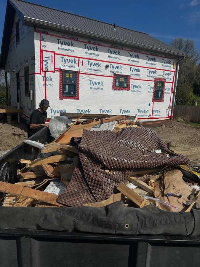 A trailer loaded with lumber offcuts and foundation membrane at a new build site