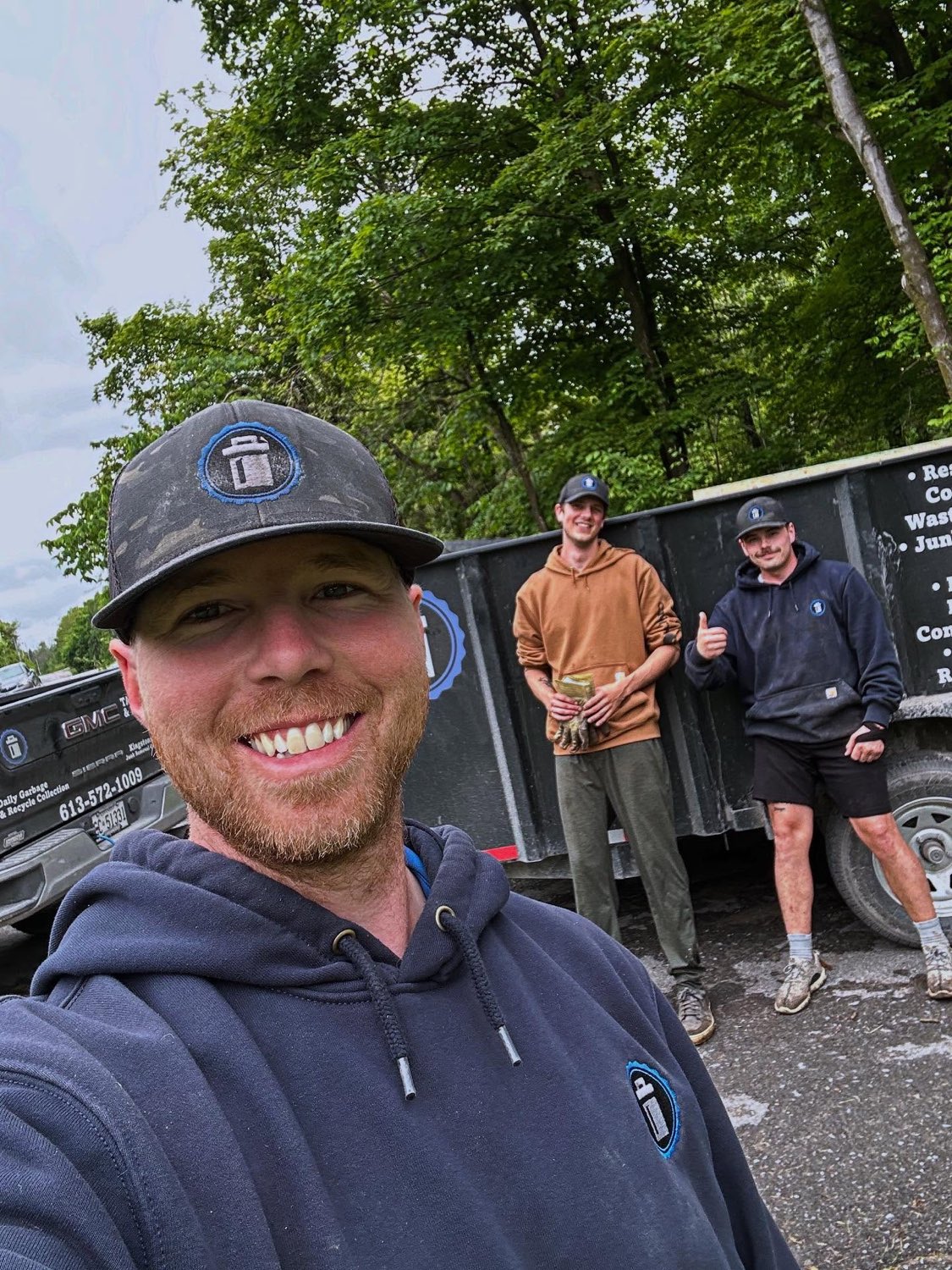 Brock Cook with two of the crew in front of the loaded trailer and company truck