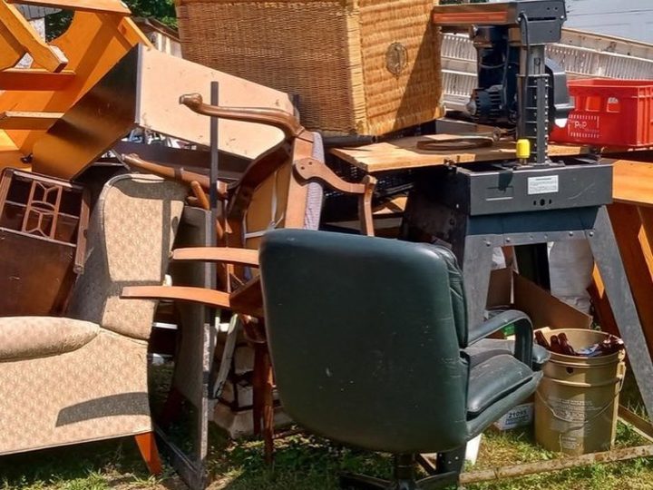 A yard stacked with old chairs, tables, a filing cabinet and an office chair staged for a Kingston junk removal pickup